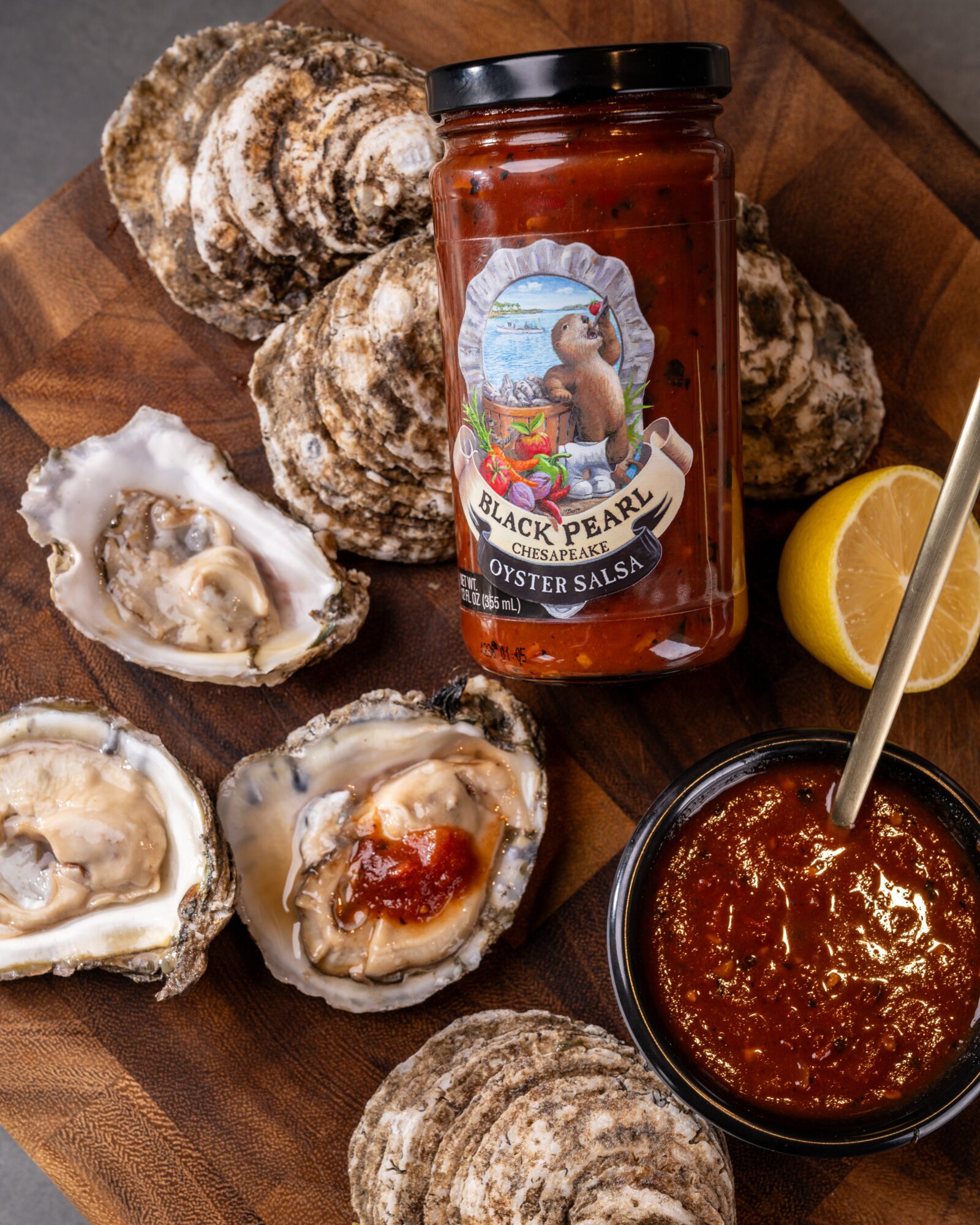 Oysters on a wooden tray with lemon, oyster sauce jar, and a bowl of sauce.