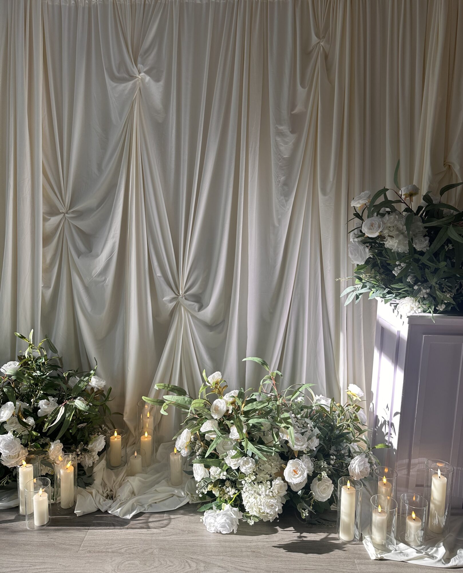 Curtain backdrop with floral arrangements and candles, creating an elegant setting.