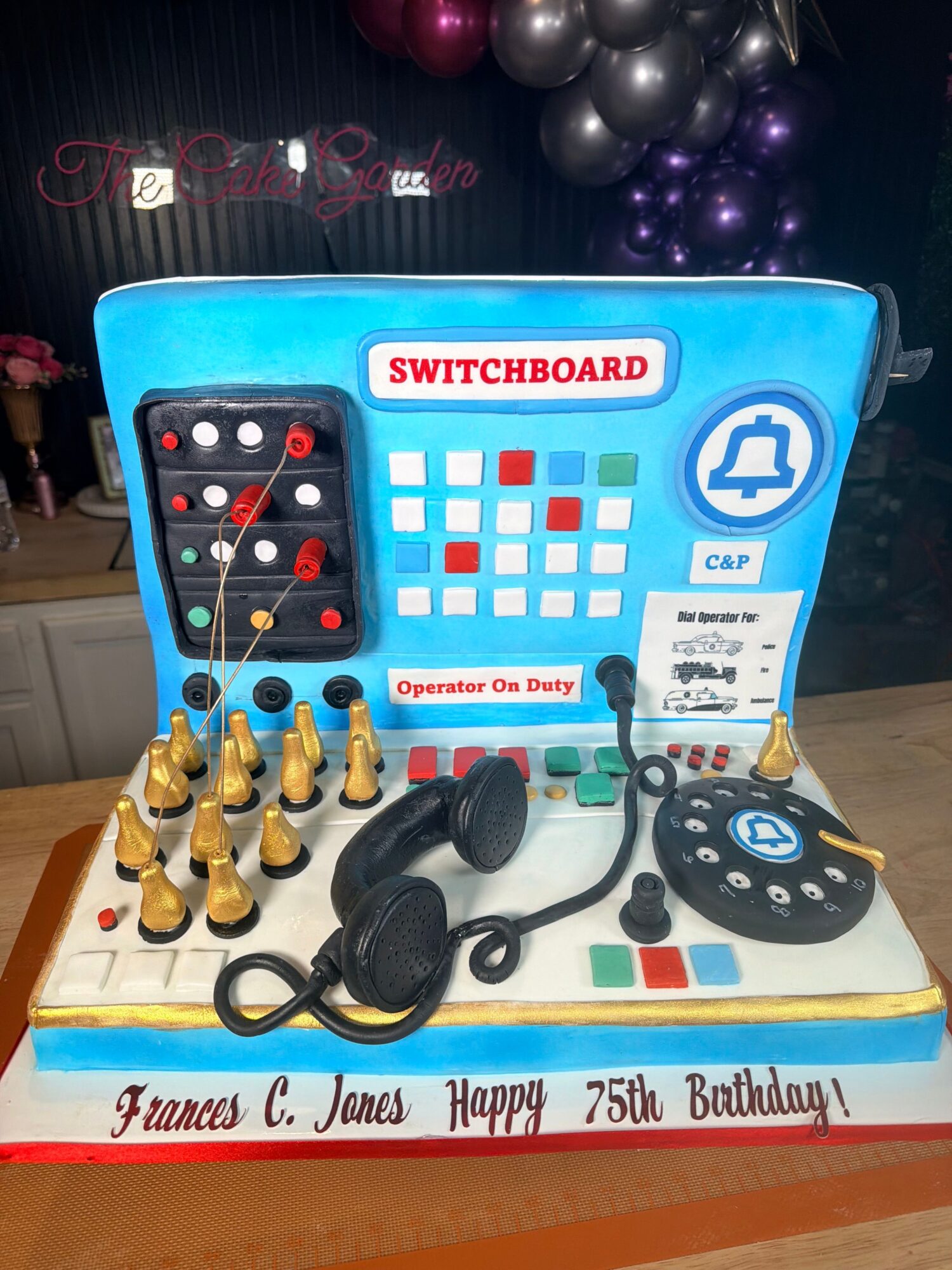 Board with game pieces, headphones, and a sign celebrating a birthday, on a table with balloons in the background.