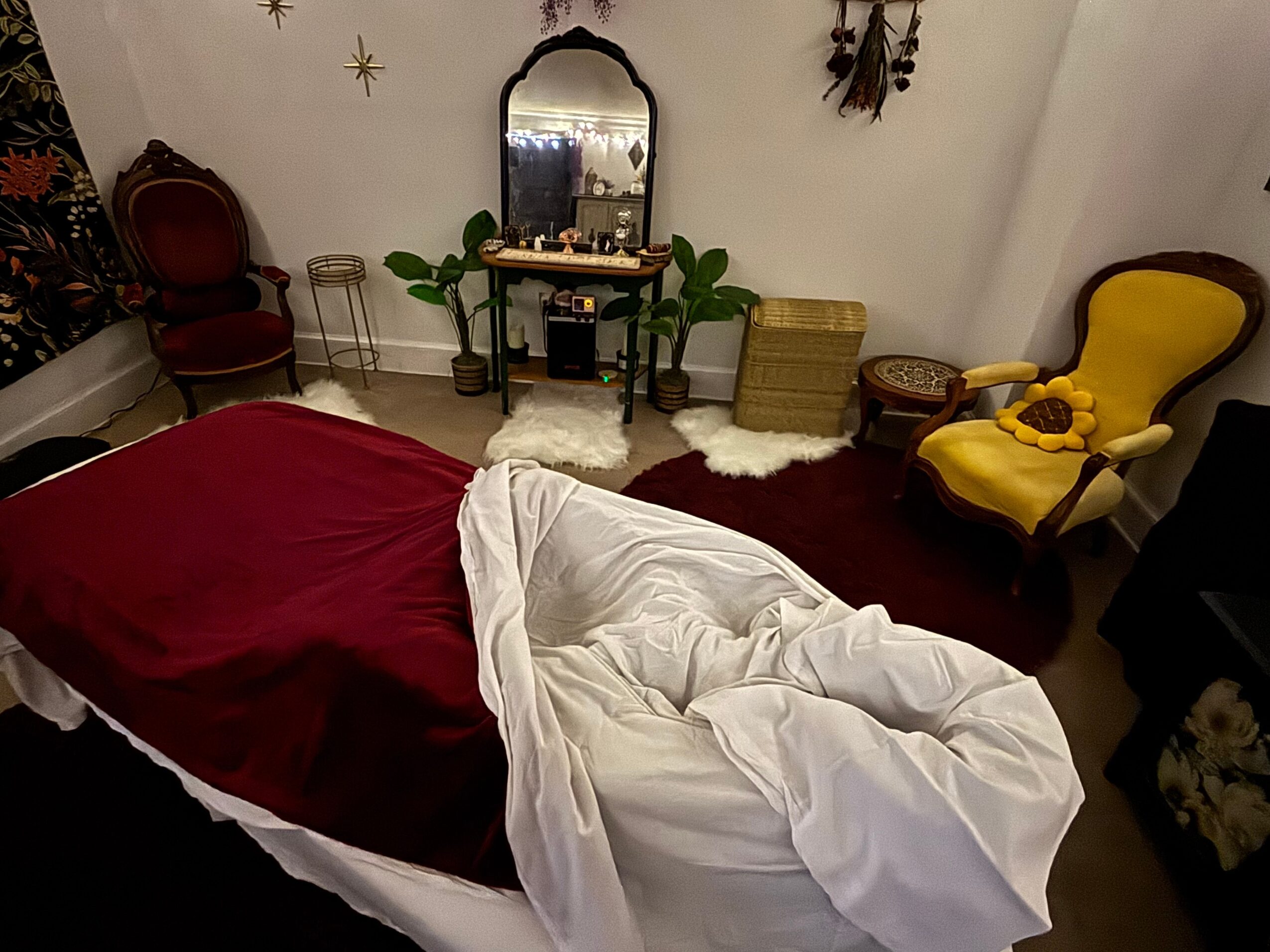 Room with a bed, yellow armchair, mirror, and decorative wall items, viewed from above.