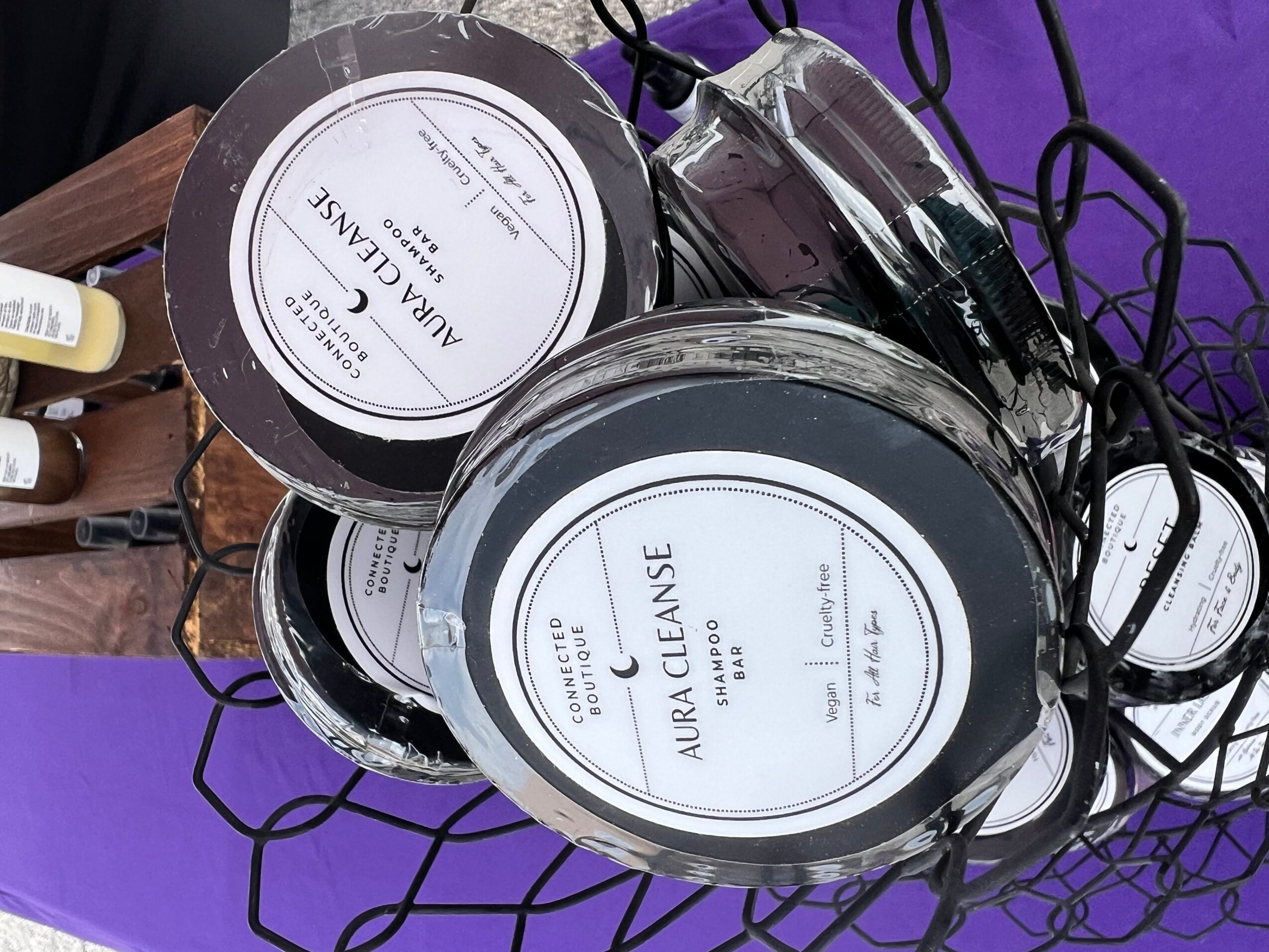 Black and white containers with labels, a glass jar, and black cords on a purple surface.