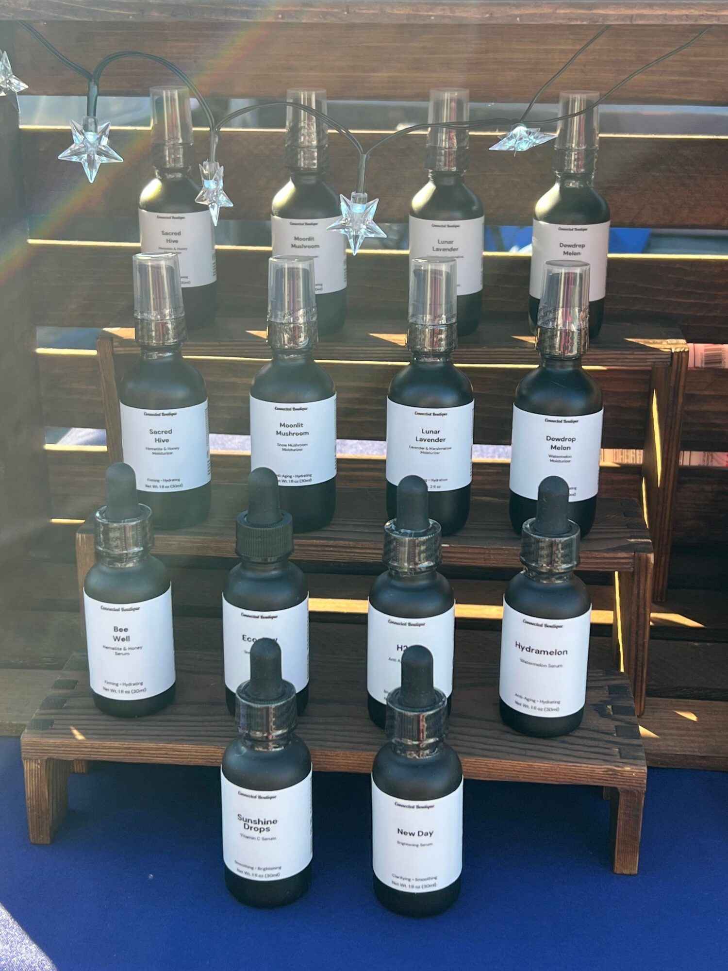 Multiple bottles and spray cans arranged on a wooden shelf, with some bottles having black caps and others white caps.