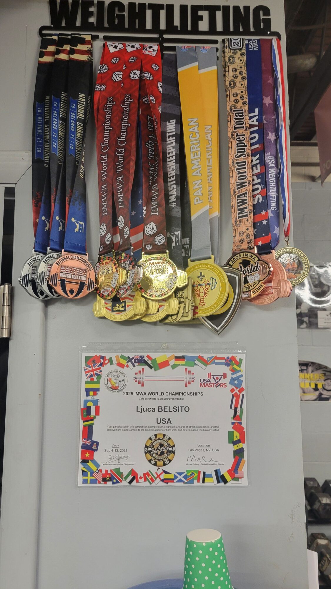 Medals and trophies displayed on a table with a colorful certificate on a white surface.