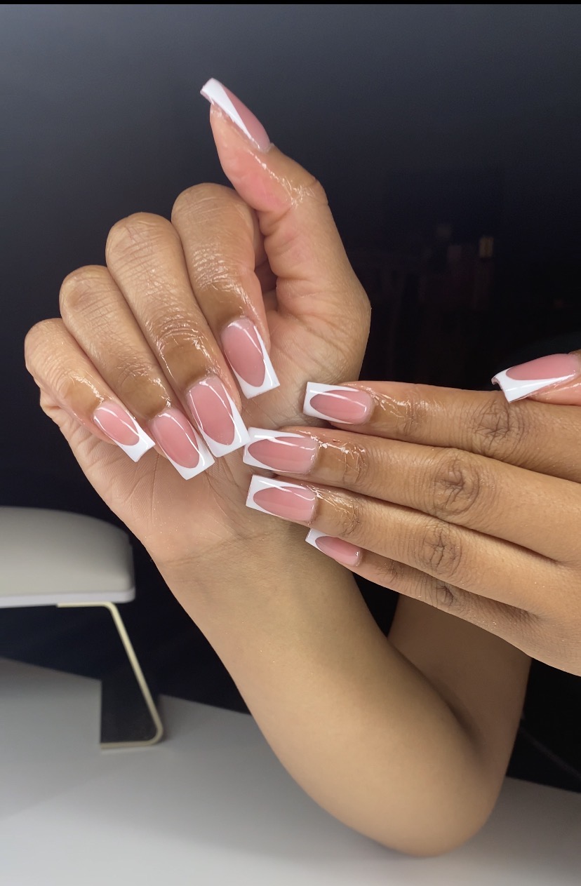 Two hands with manicured nails, one with light pink and white nails, the other with darker skin tone and similar nails, intertwined.