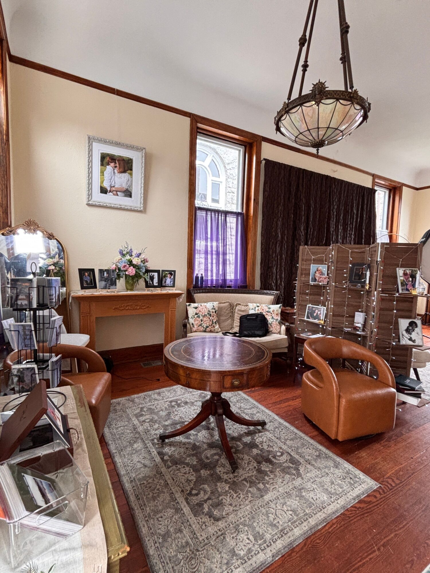 Living room with a sink, chairs, a window with purple curtains, and a patterned rug on wooden floor.