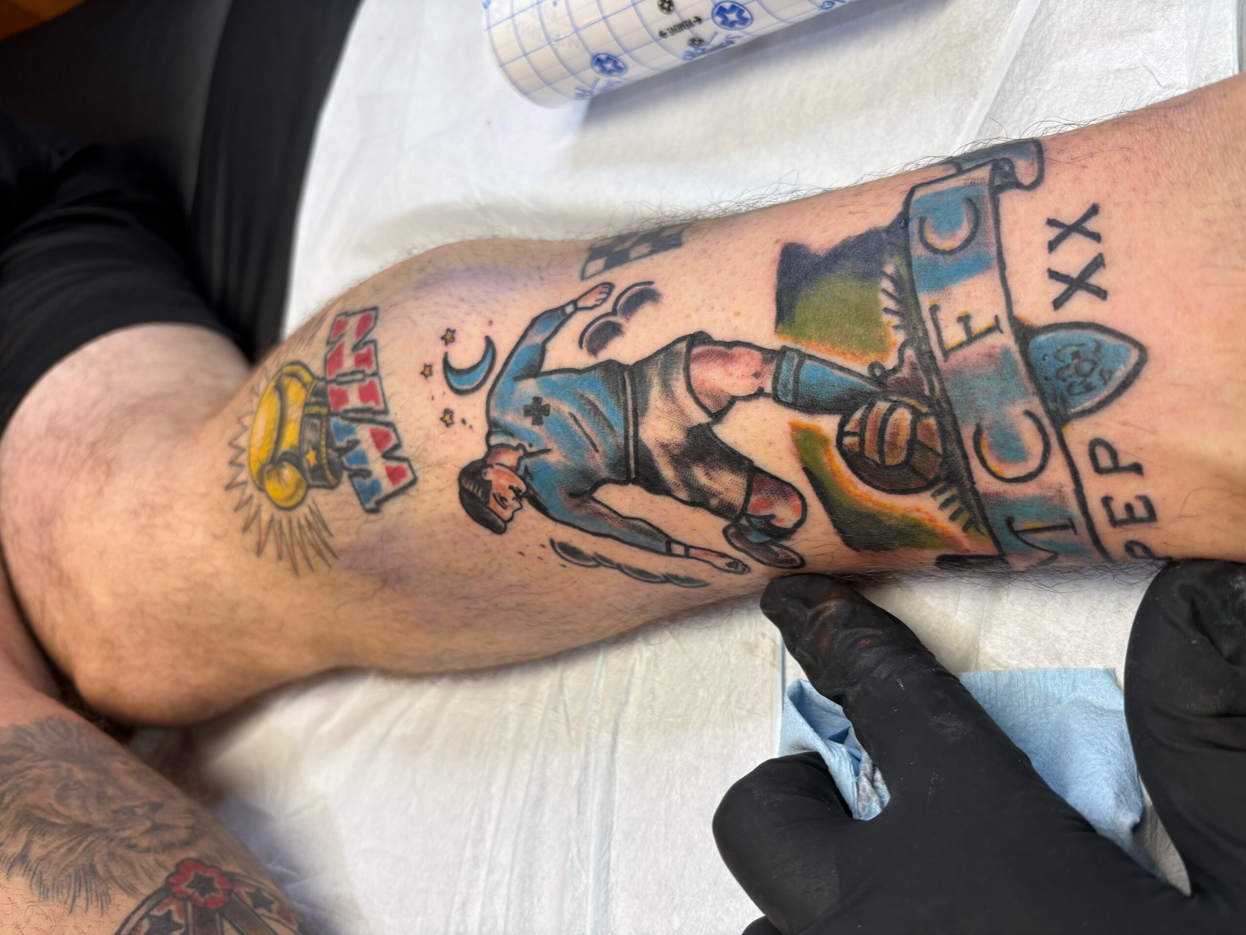 Tattoo of a woman in a dress walking on a path, with a sunset, clouds, and text, on a person's arm.