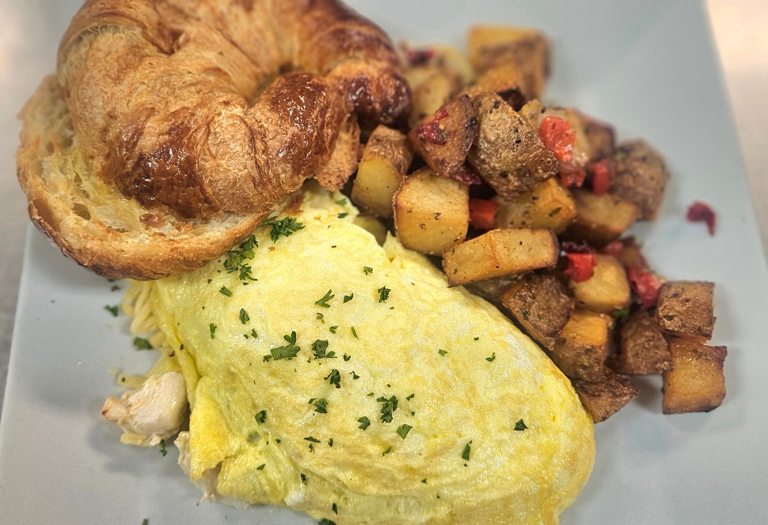Scrambled eggs with herbs, toasted bread, and diced cooked potatoes with vegetables on a plate.