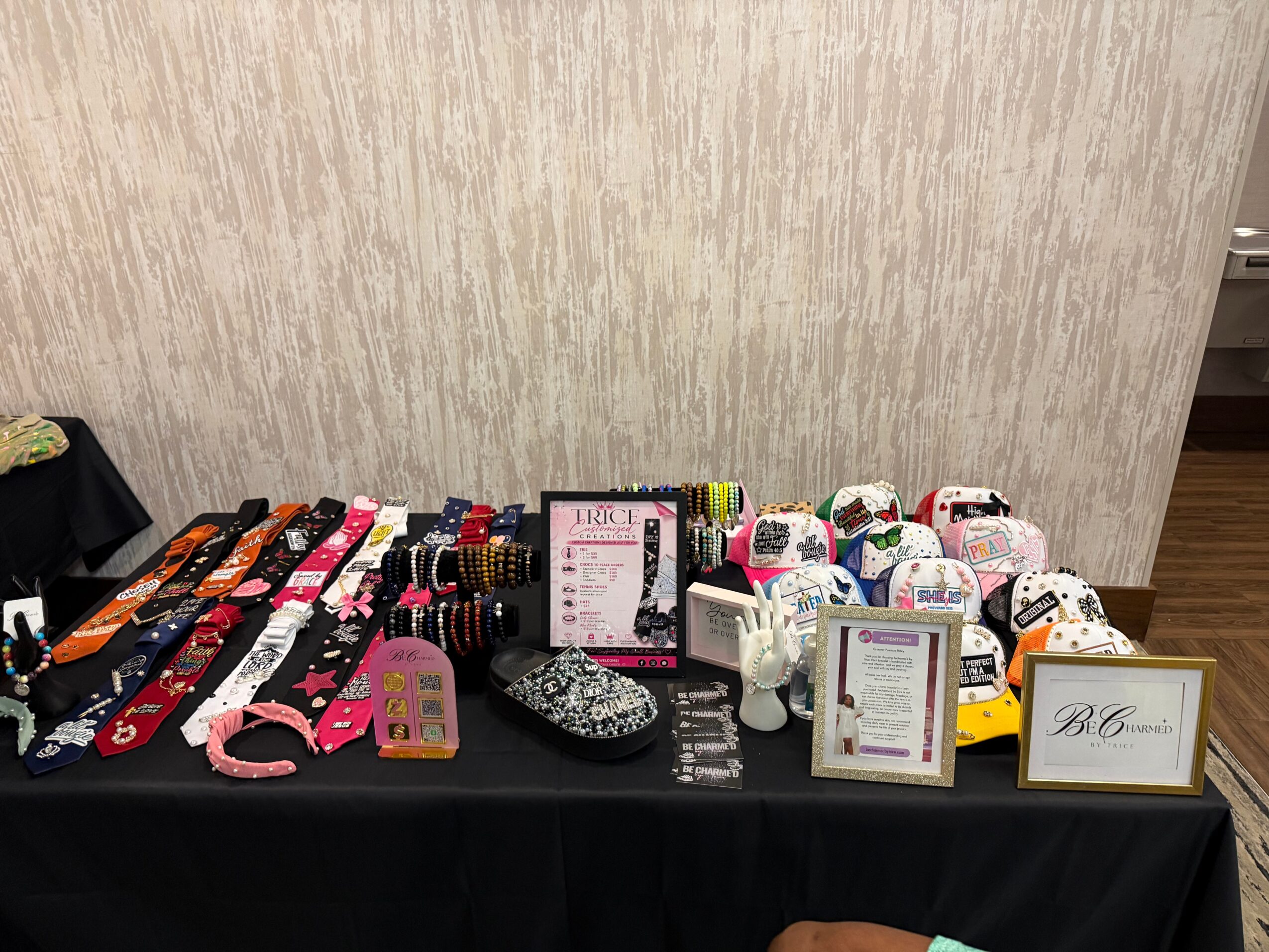 Display table with various accessories, jewelry, and small items arranged on a black tablecloth against a plain wall.