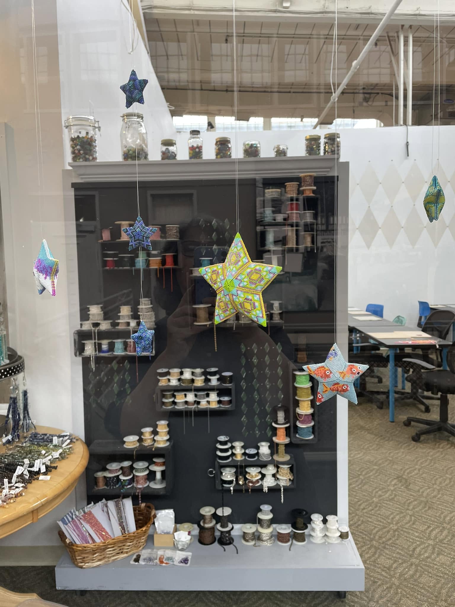 Display case with jars and containers, star-shaped decorations, and a basket of items inside a store or office.