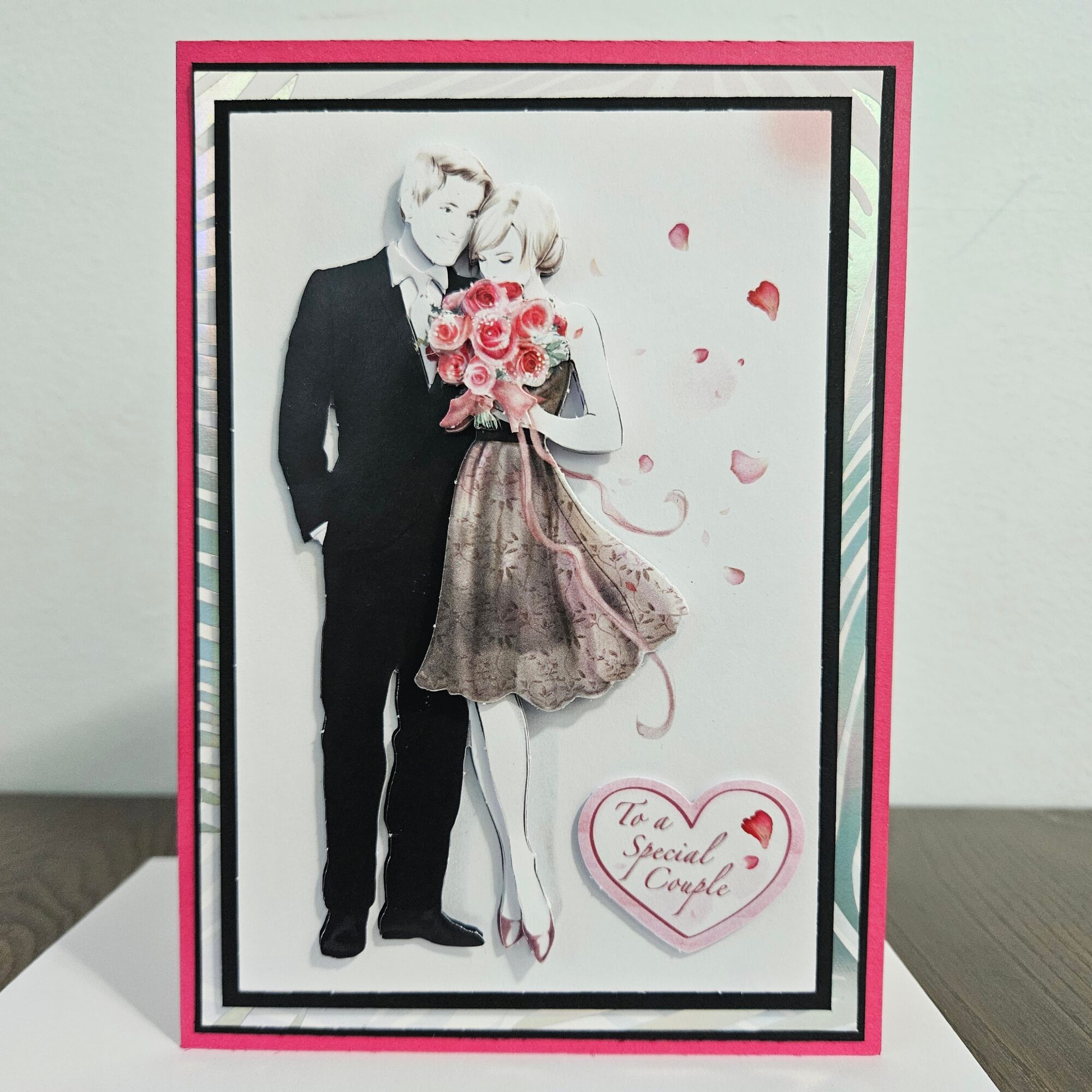 A greeting card with a black and white photo of a couple, a bouquet of roses, and a heart with text.