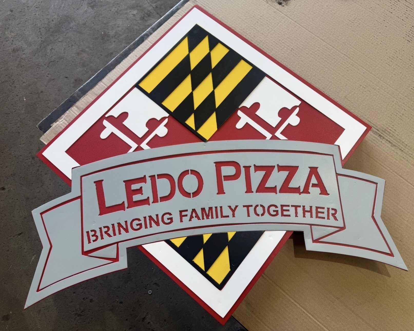 Two signs, one with Maryland state flag pattern and another for Ledo Pizza, overlapping on a surface.