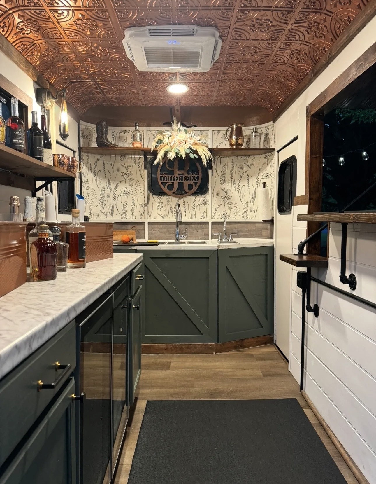 Kitchen with green cabinets, marble countertop, wooden floor, and decorative ceiling, featuring a floral arrangement above the sink.