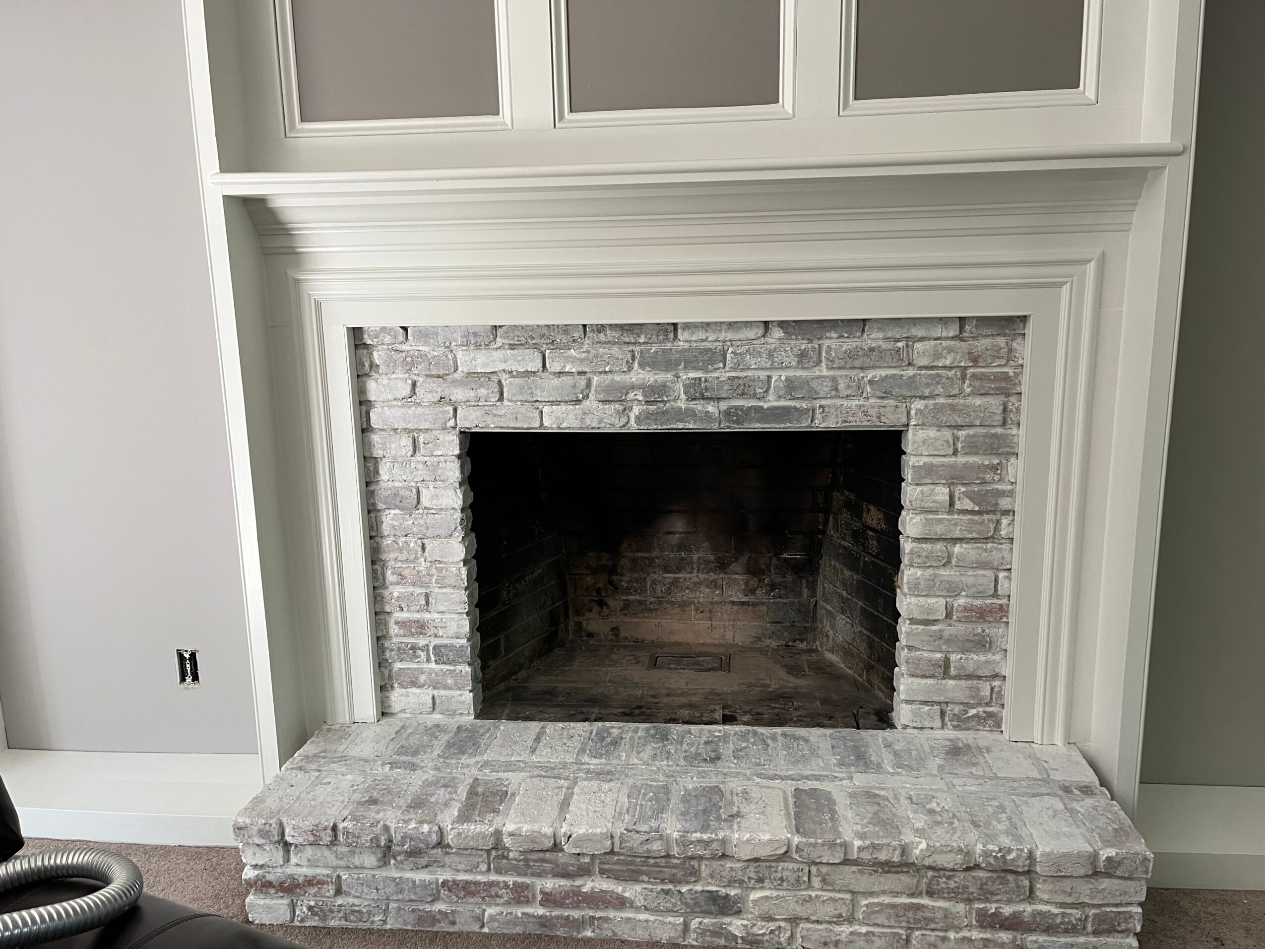 Fireplace with brick interior and white mantel, no fire or objects, in a room with gray walls.