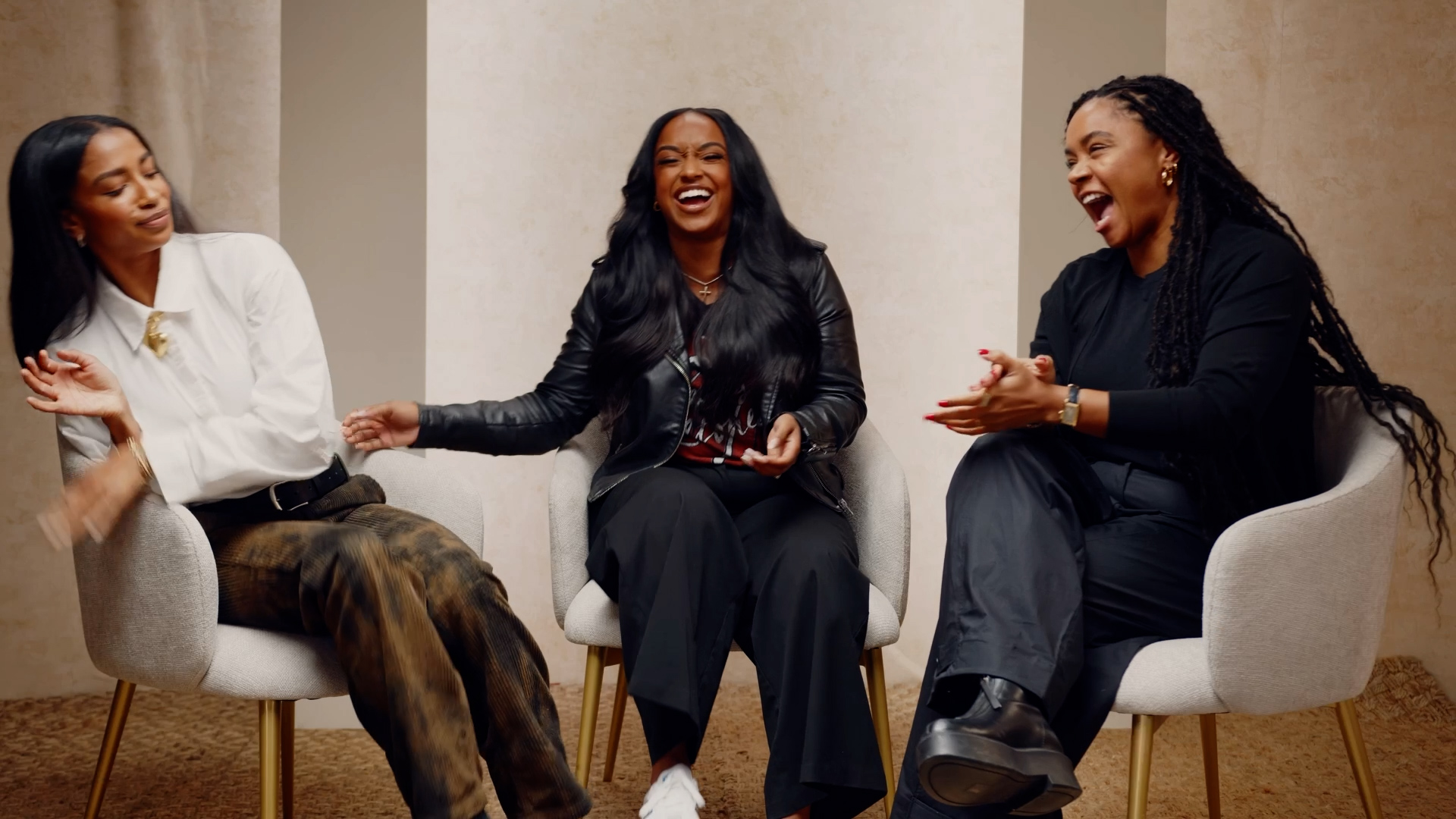 Three women sitting and laughing together in a room, engaging in conversation.
