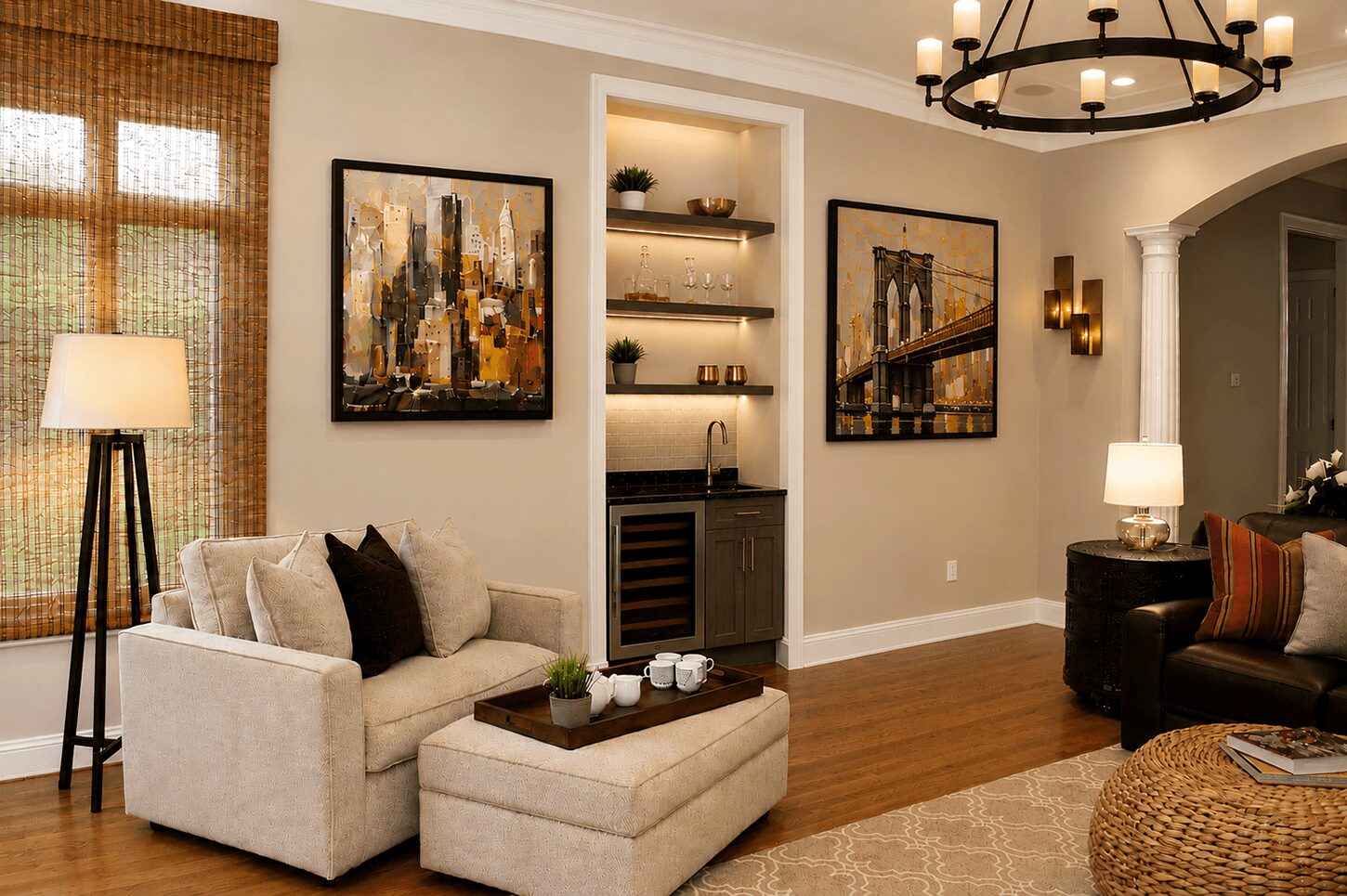 Living room with beige sofa, black armchair, artwork, shelves, and a chandelier, with hardwood floors and a window with curtains.