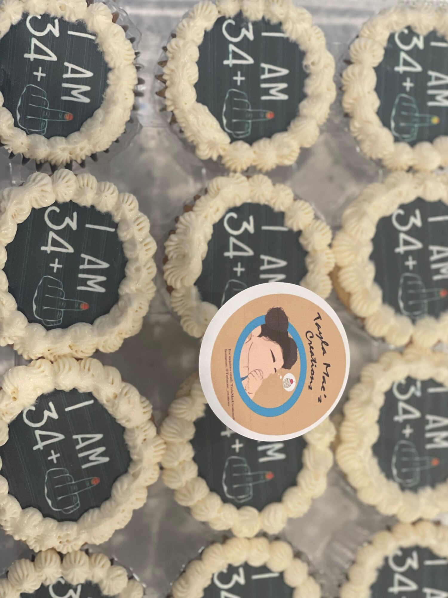 Group of cupcakes with black toppers and a circular sticker featuring a woman, text, and a light background.