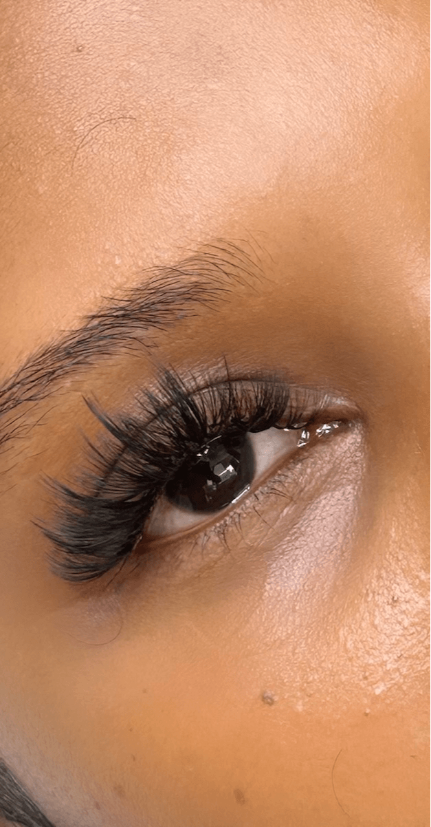 Close-up of a person's eye with long eyelashes and smooth skin.