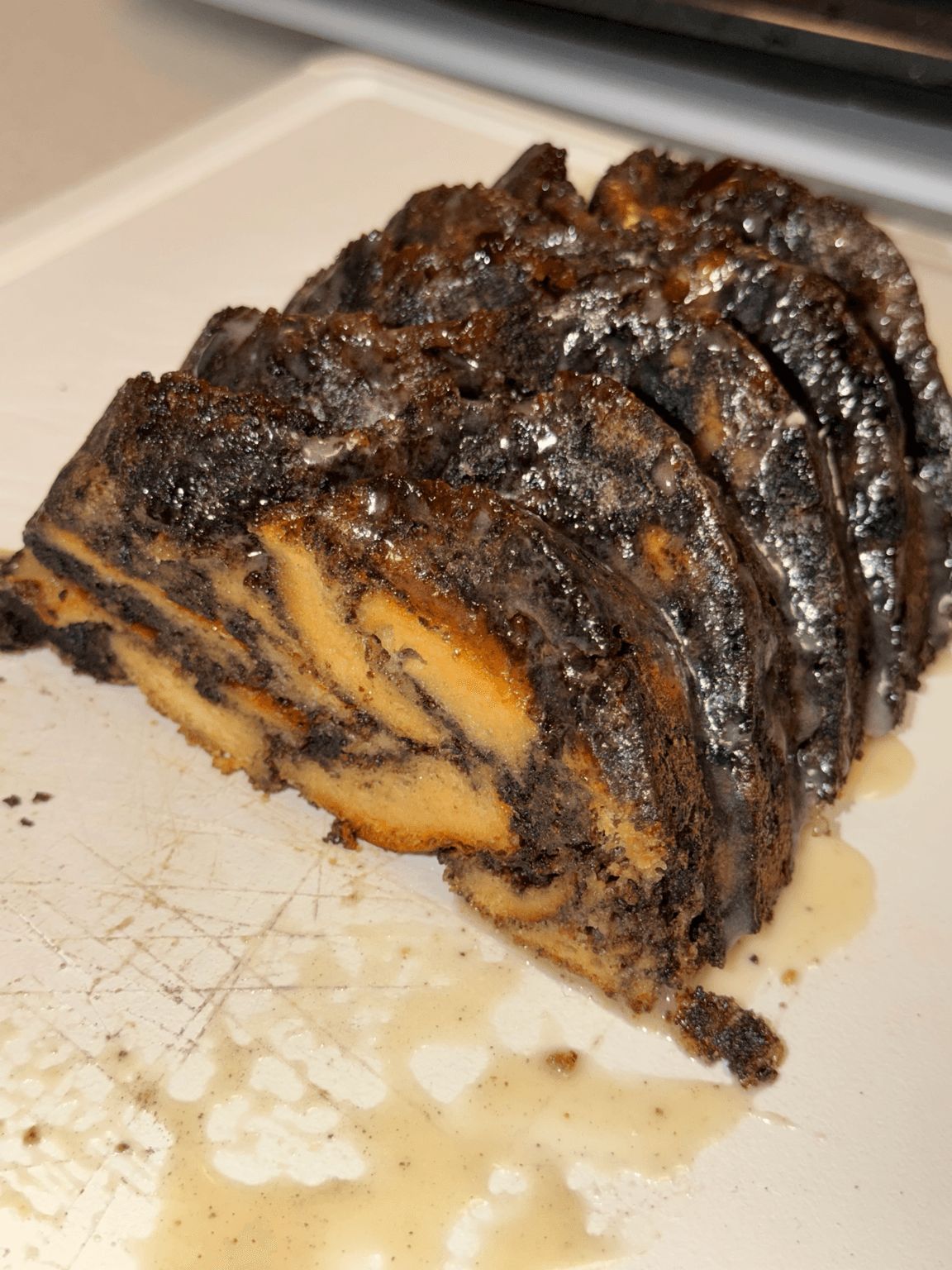 Sliced chocolate and vanilla swirl cake with a dark, textured crust on a white surface.
