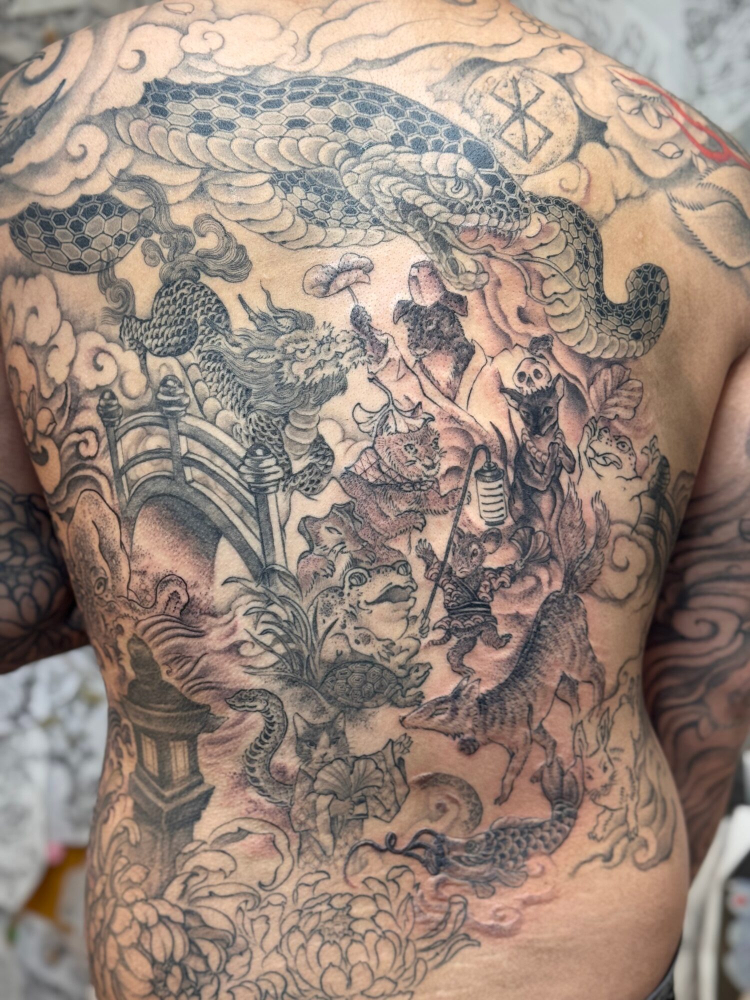 Intricate tattoo covering the chest with a dragon, clouds, and traditional Asian elements, detailed line work and shading.