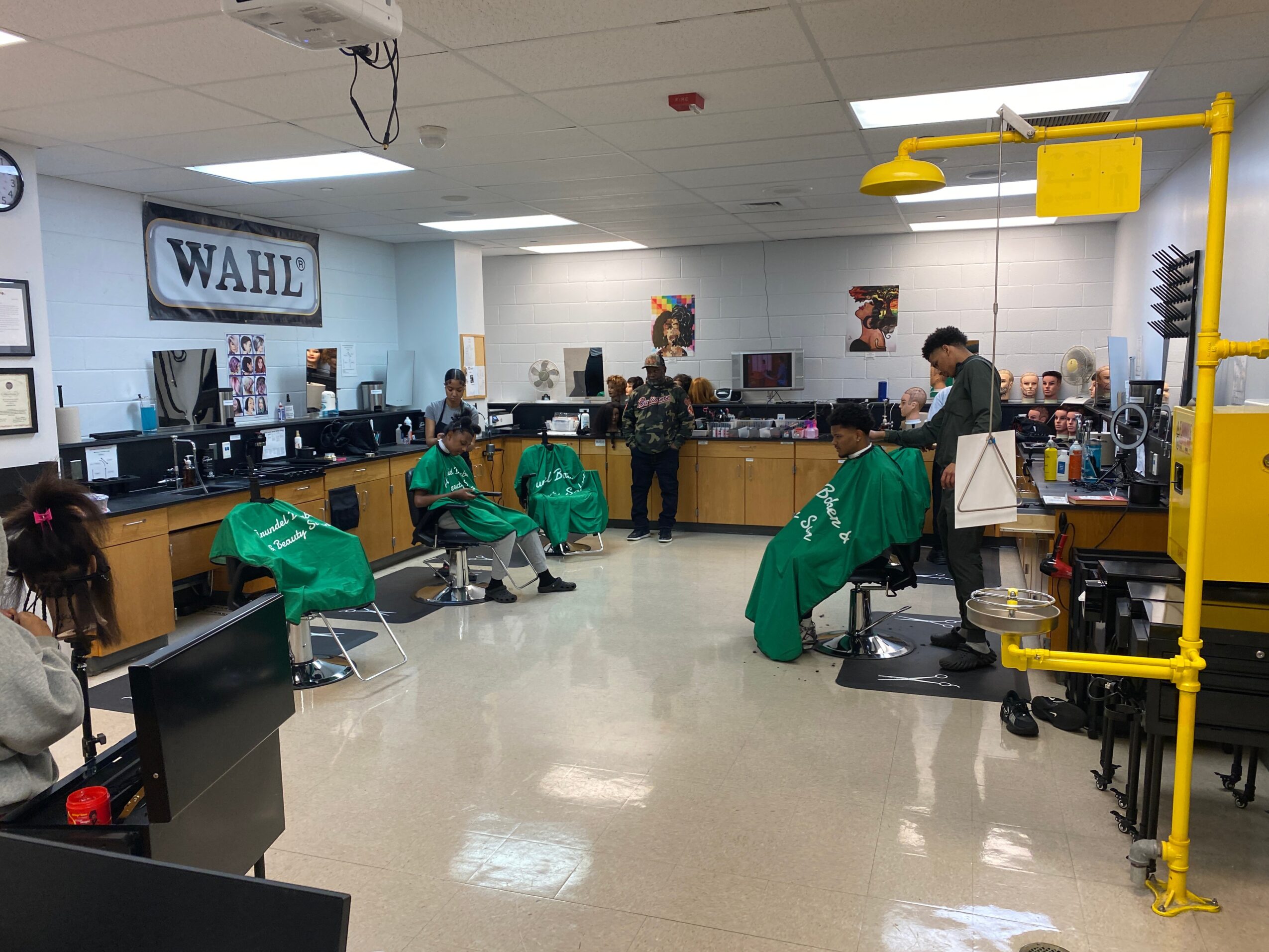 Barbershop interior with four people getting haircuts, mirrors, and salon equipment, and a