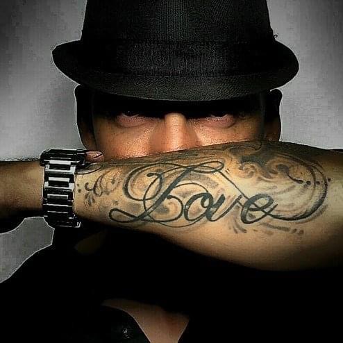 Person wearing a black hat and watch, with a tattooed arm displaying the word 'Save' in cursive script.