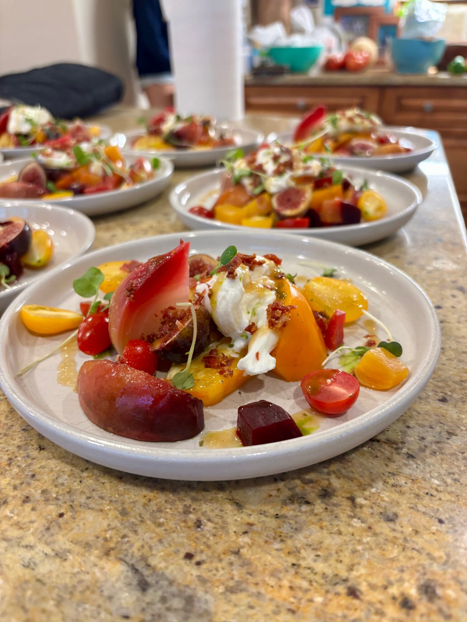 Multiple plates of colorful fruit salad with various fruits and toppings on a kitchen counter.