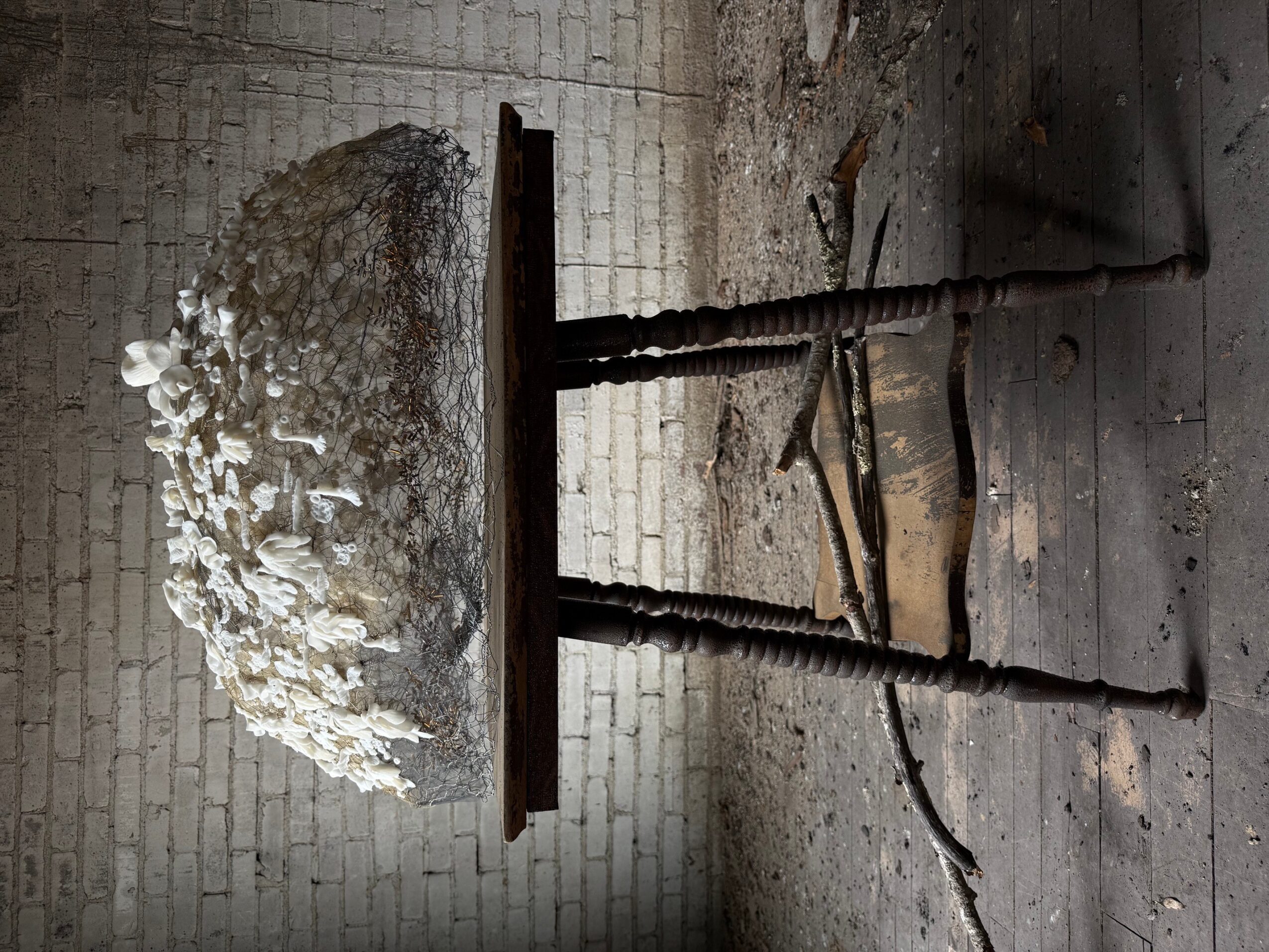 A table with a large, irregularly shaped stone or sculpture on top, set against a brick wall background.