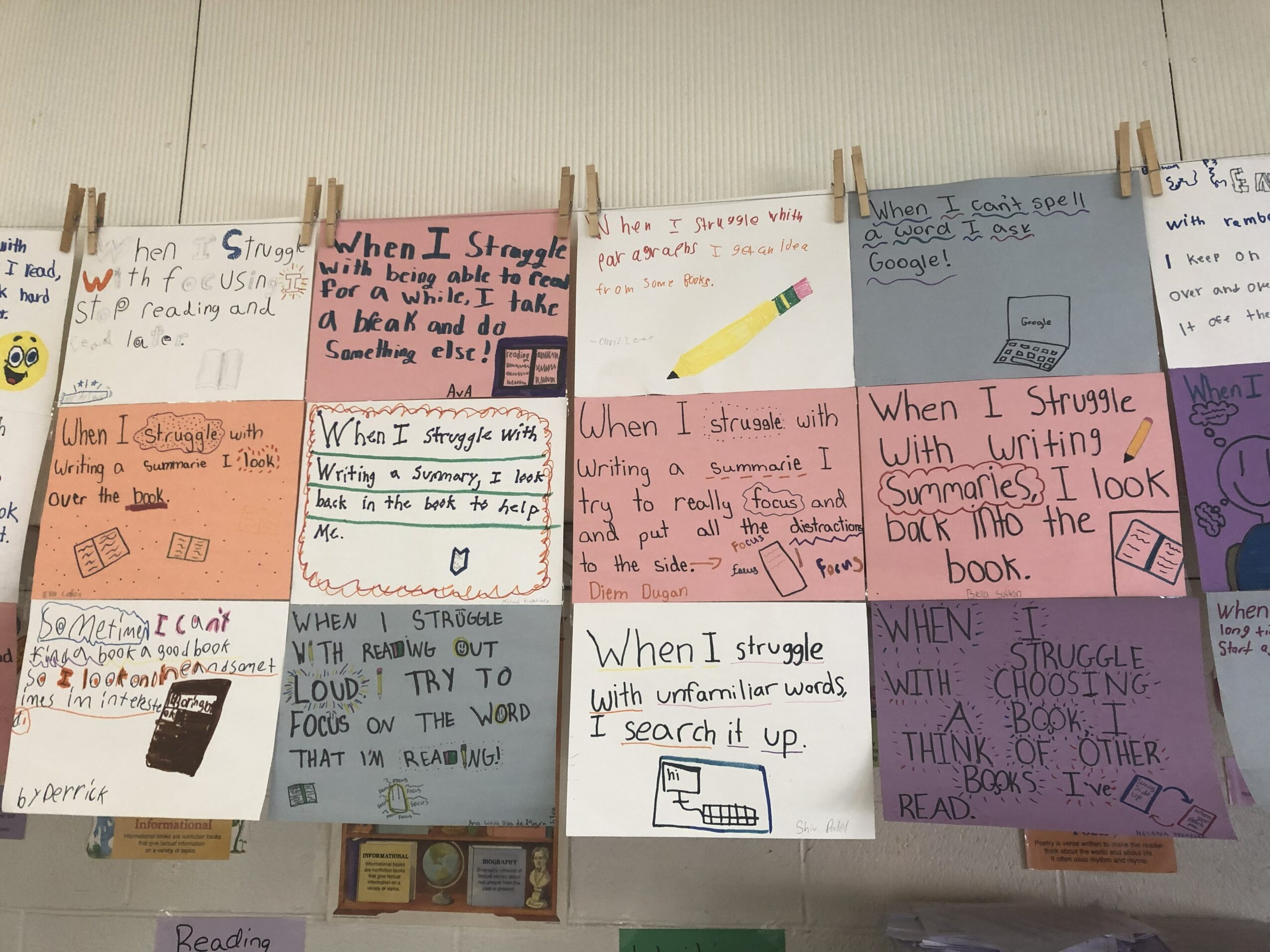 Multiple handwritten notes and drawings on paper, clipped to a line with clothespins, some with pink and white backgrounds.