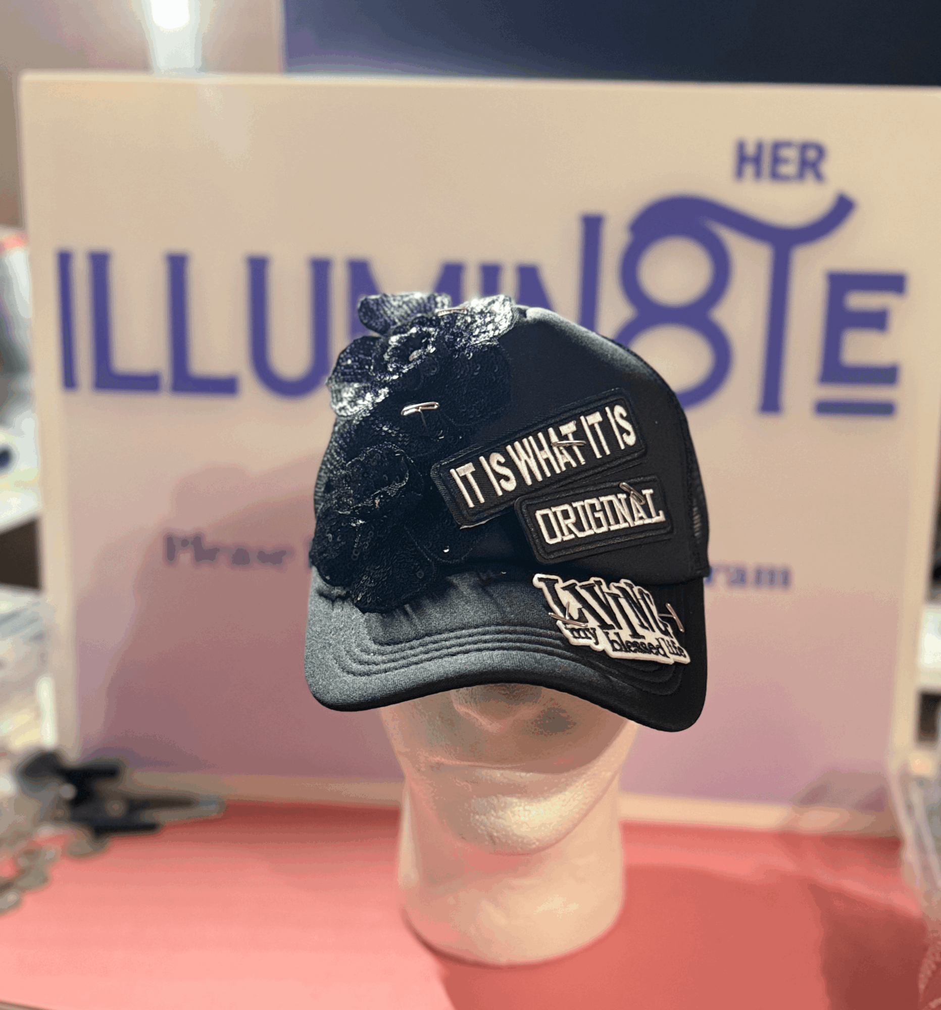 Cap with text, placed on a mannequin head, in front of a pink and purple background with text. Word count: 20